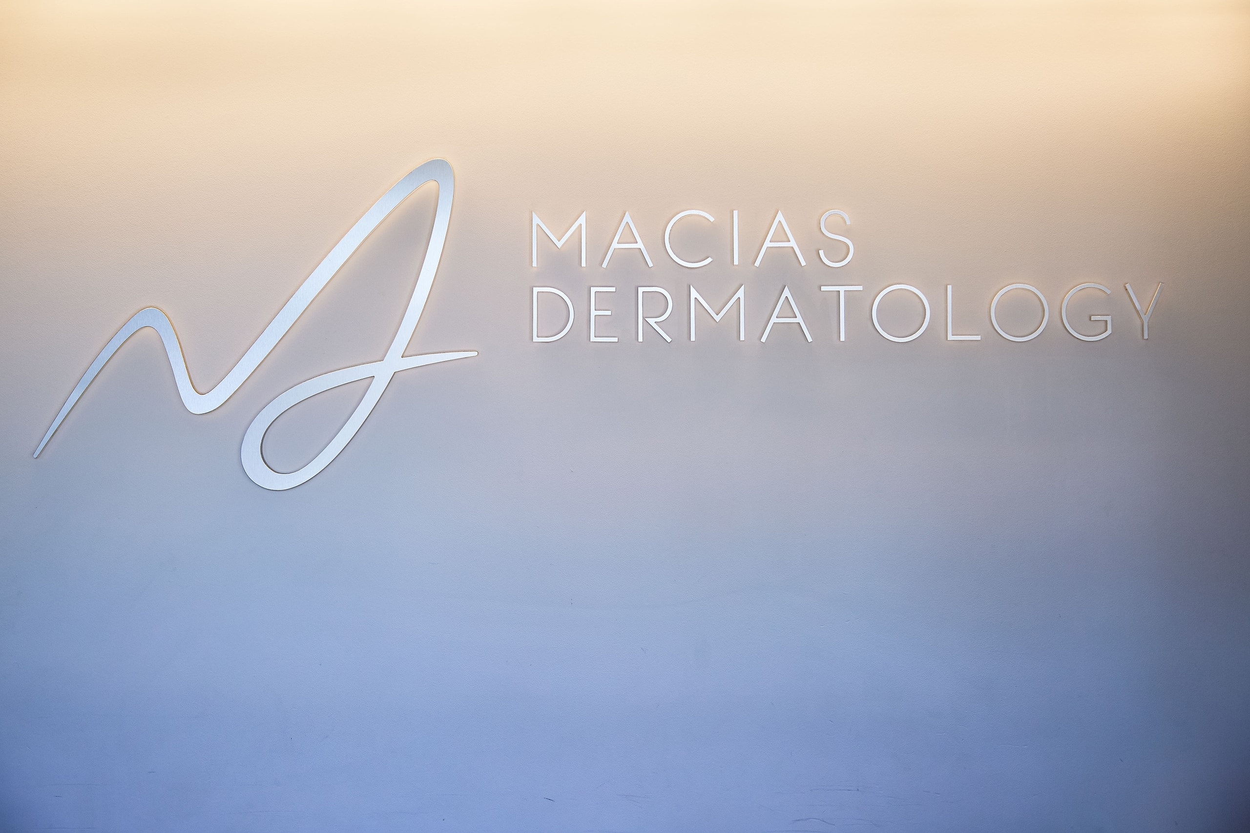 The Macias Dermatology wordmark etched in glass