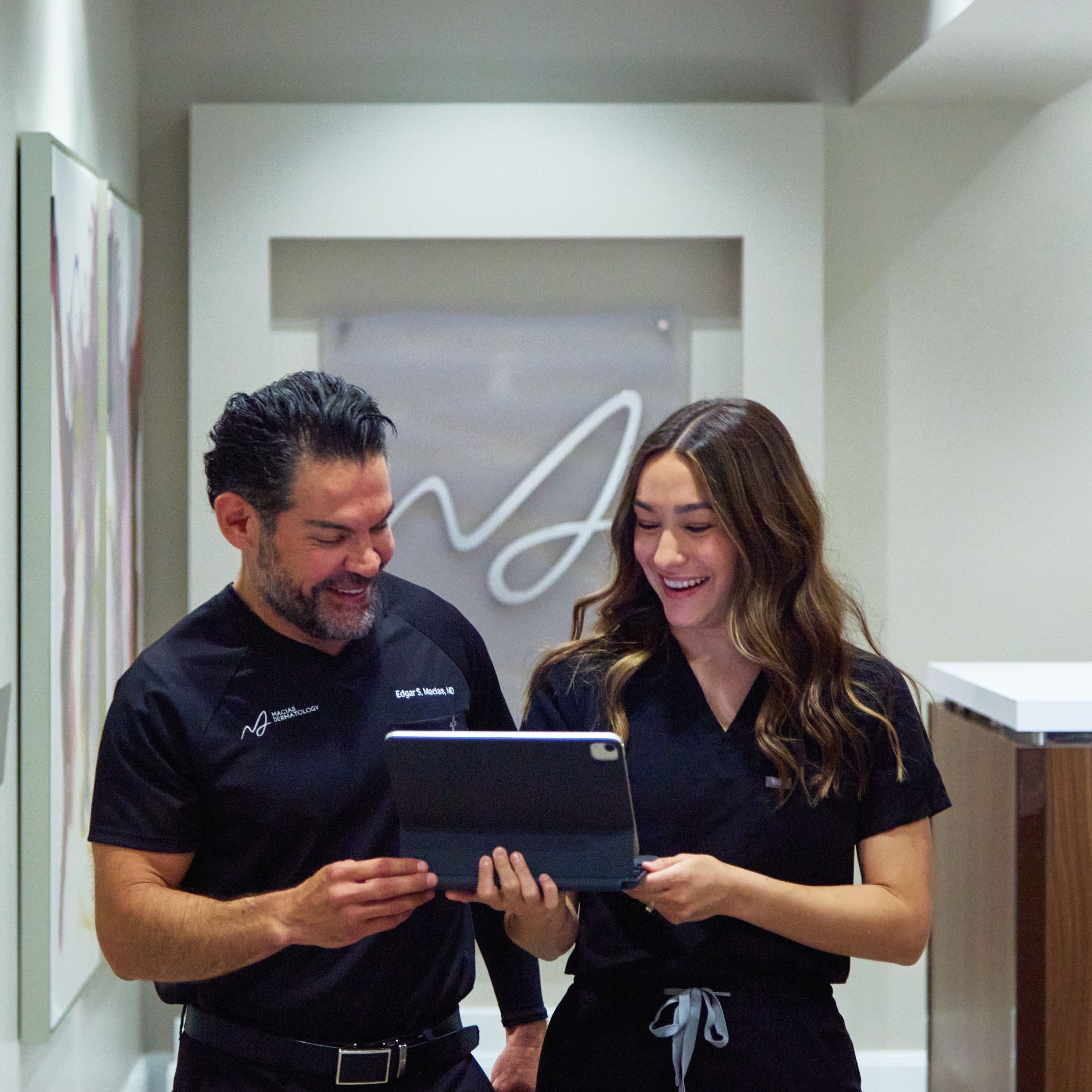 Dr. Edgar S. Macias reviewing a chart with a physician assistant beneath the practice wordmark
