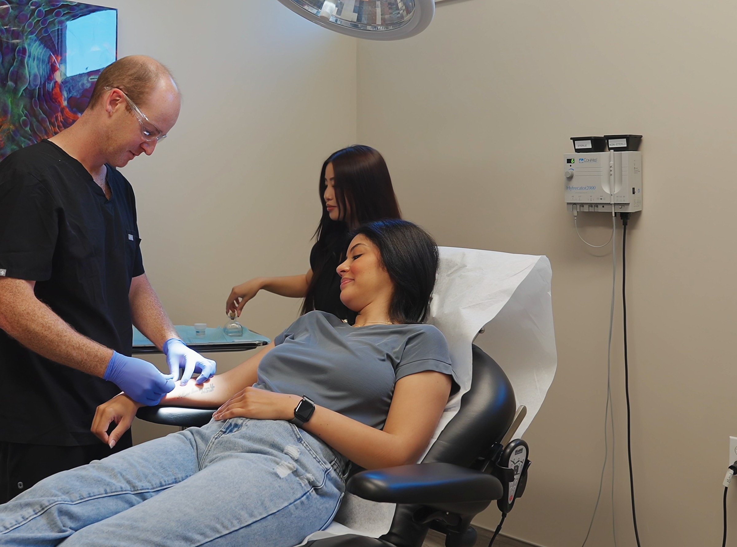 A smiling patient with two clinicians as a treatment is prepared
