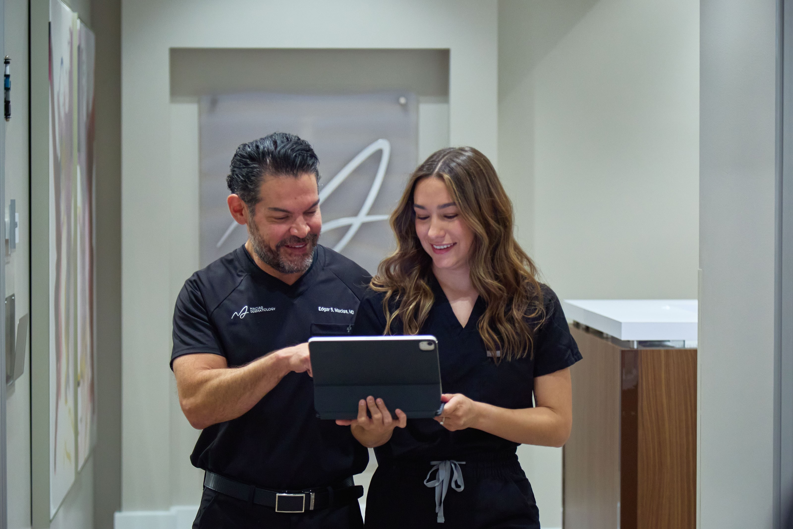 Dr. Macias and a team member reviewing a treatment plan on a tablet in the clinic hallway