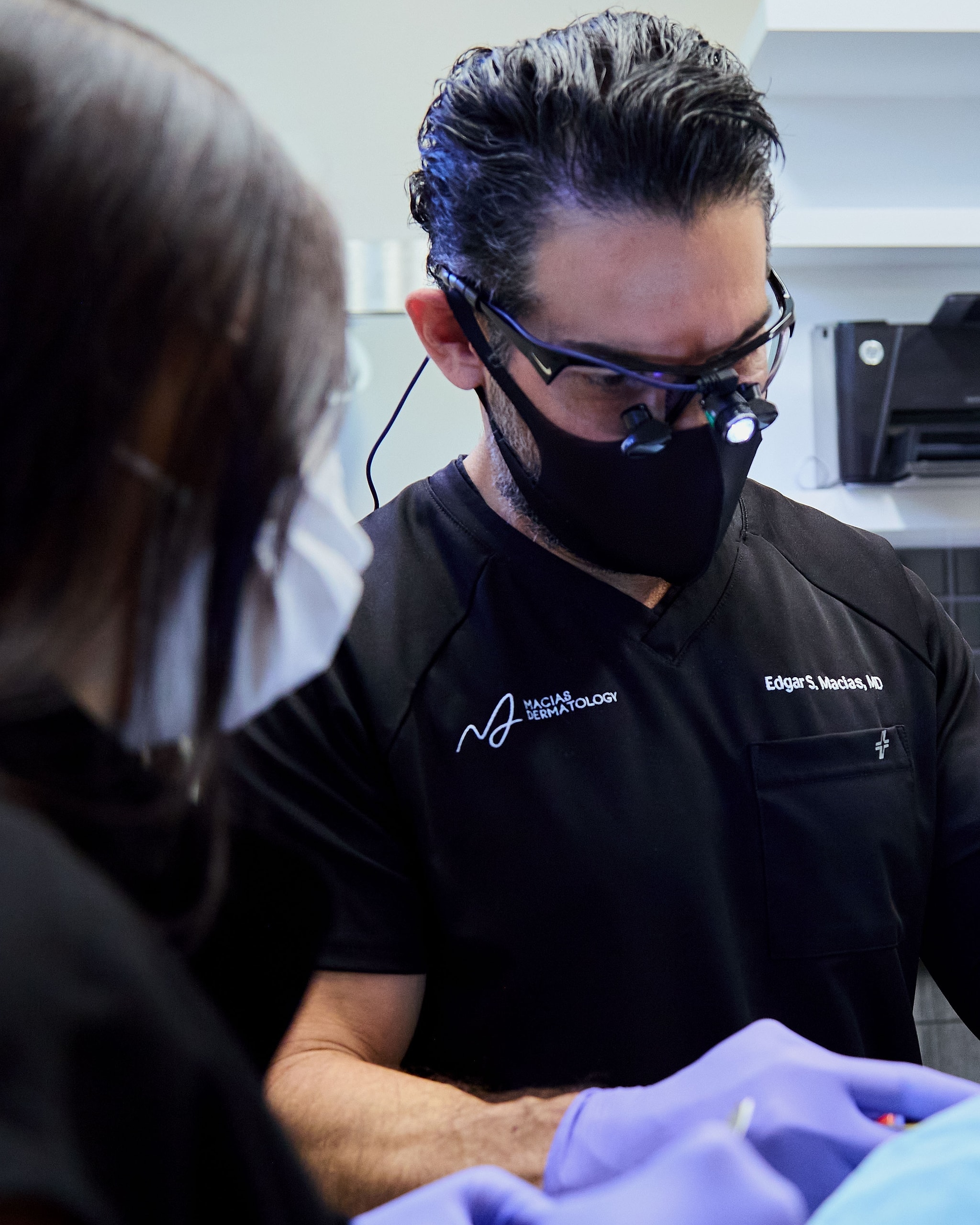 El Dr. Edgar Macias con lupas quirúrgicas realiza un procedimiento en la sala de tratamiento