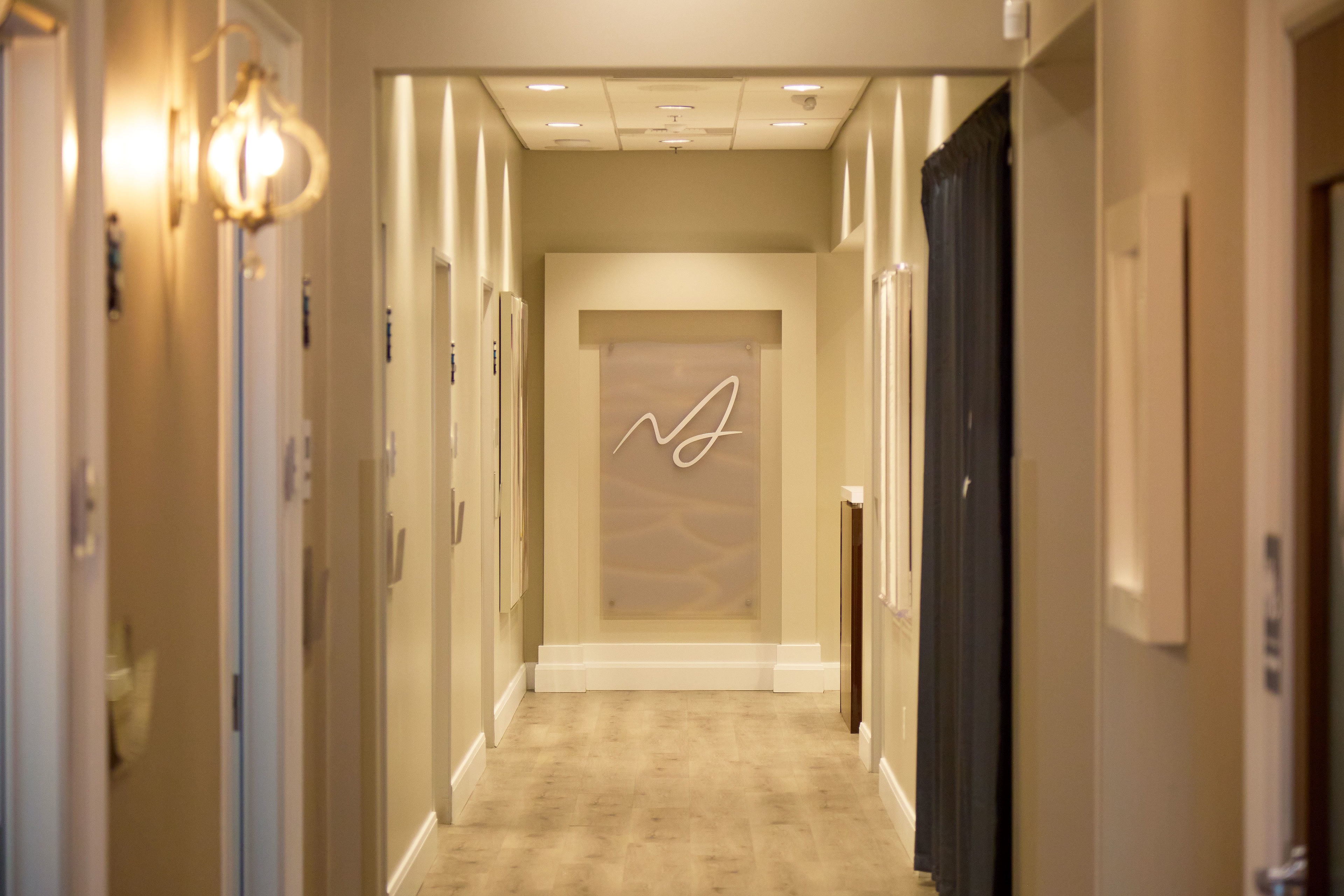 The Macias Dermatology hallway with the backlit practice monogram
