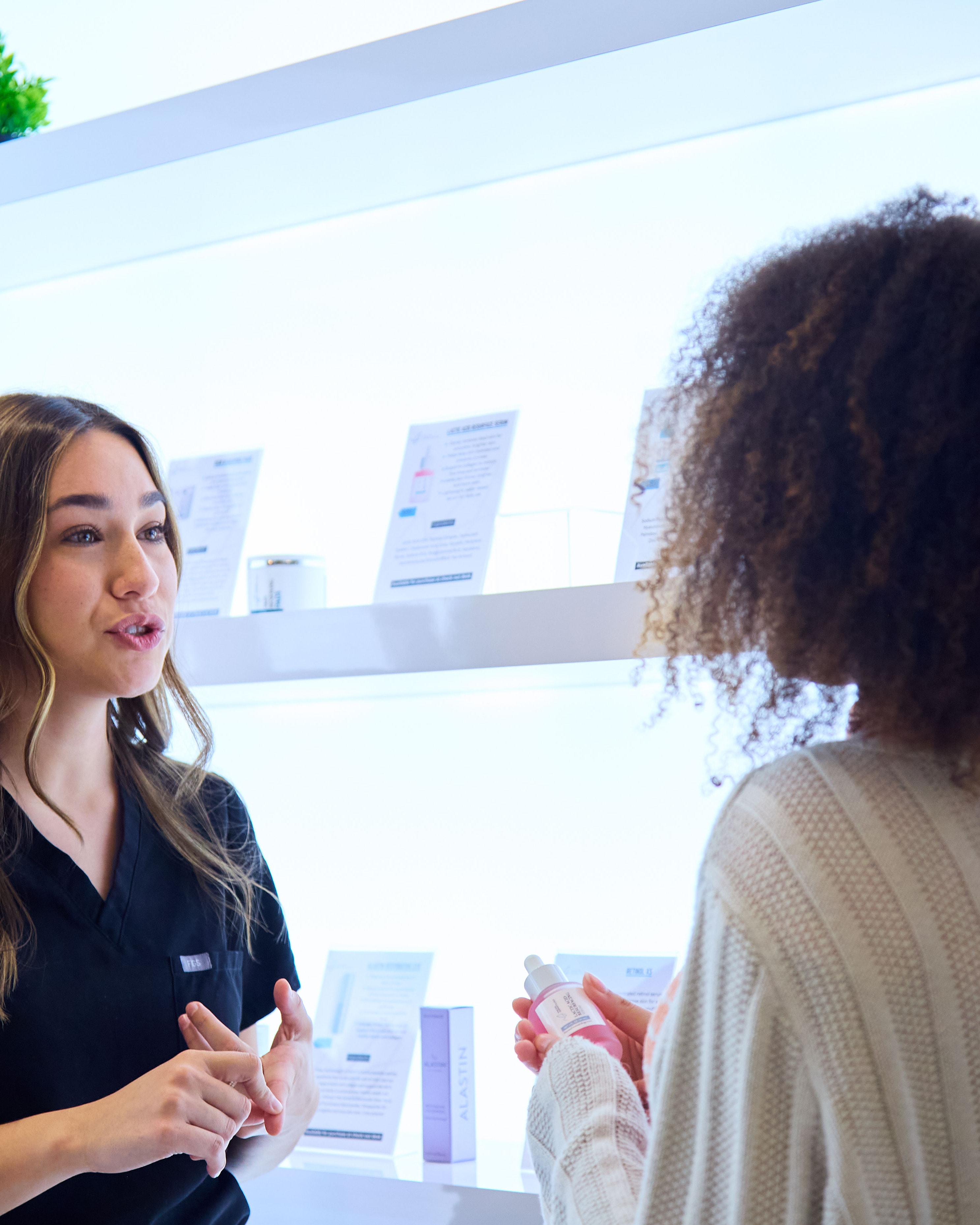 A physician assistant talking with a patient at the skincare wall