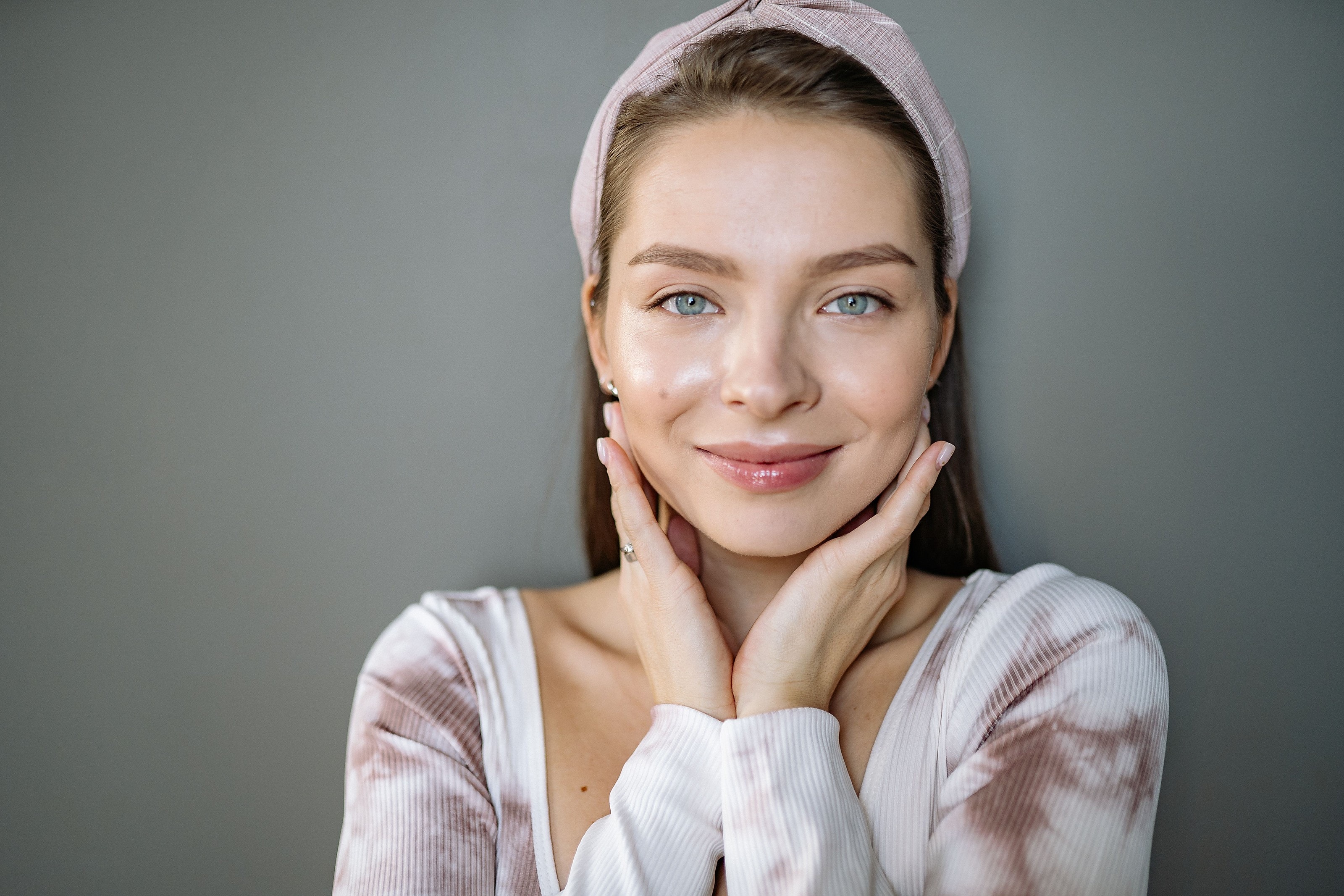 A woman with naturally glowing skin, hands framing her face