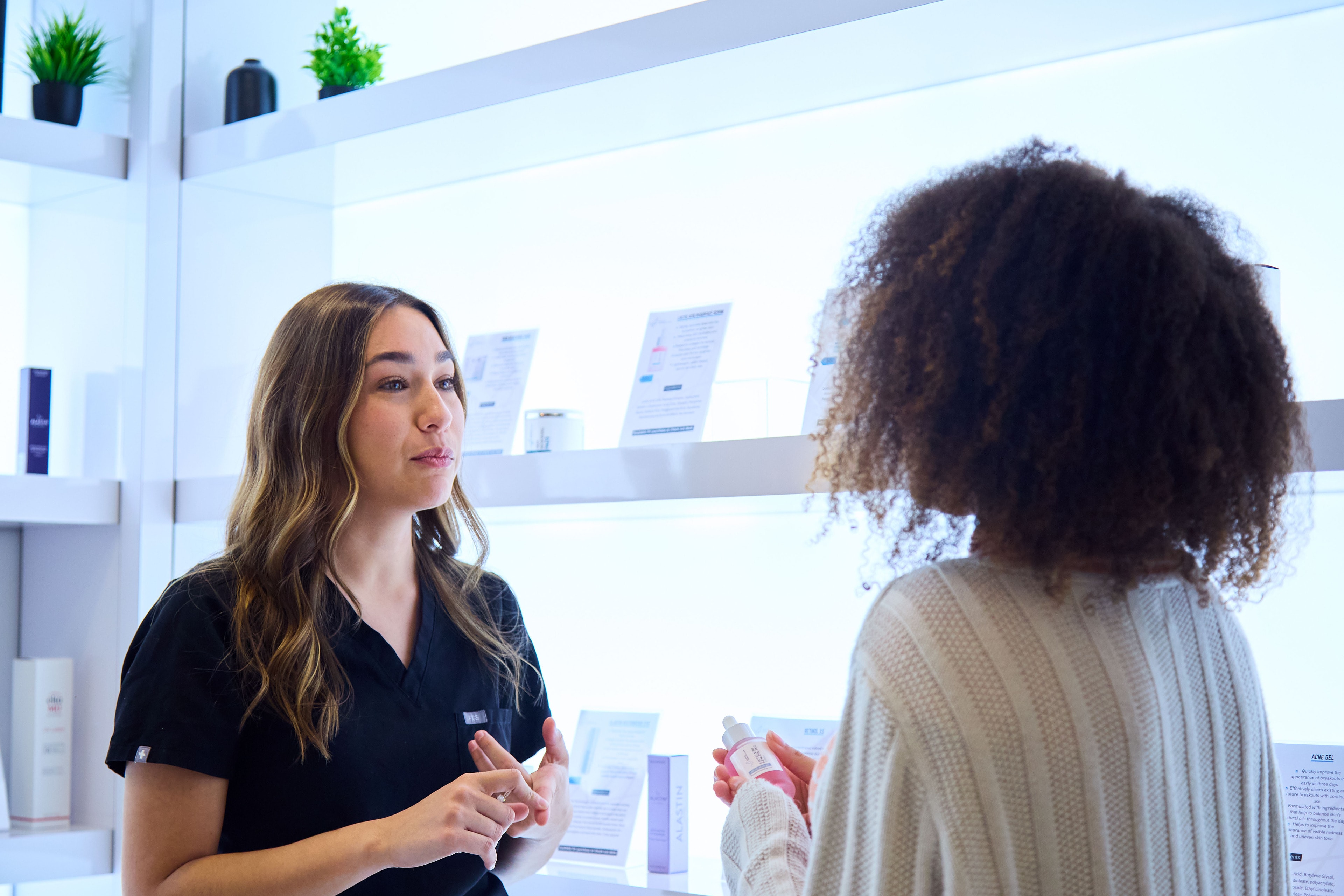 A team member walking a patient through the skincare wall at Macias Dermatology