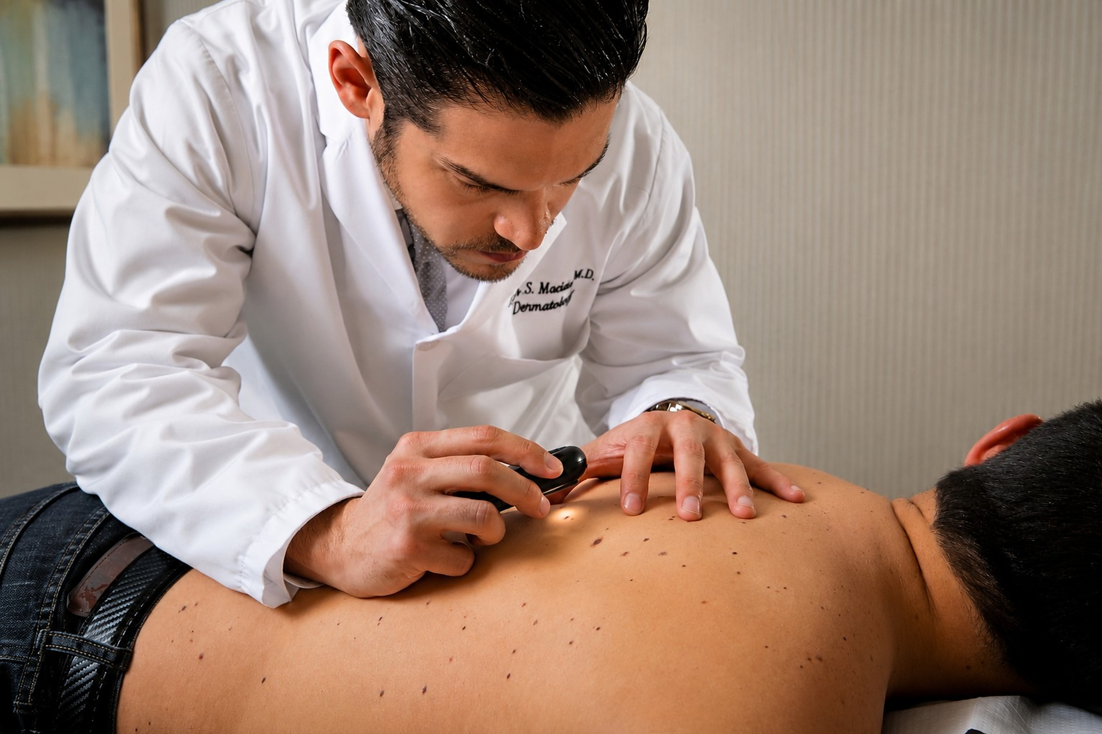 Dr. Macias examining a patient's back with a dermatoscope