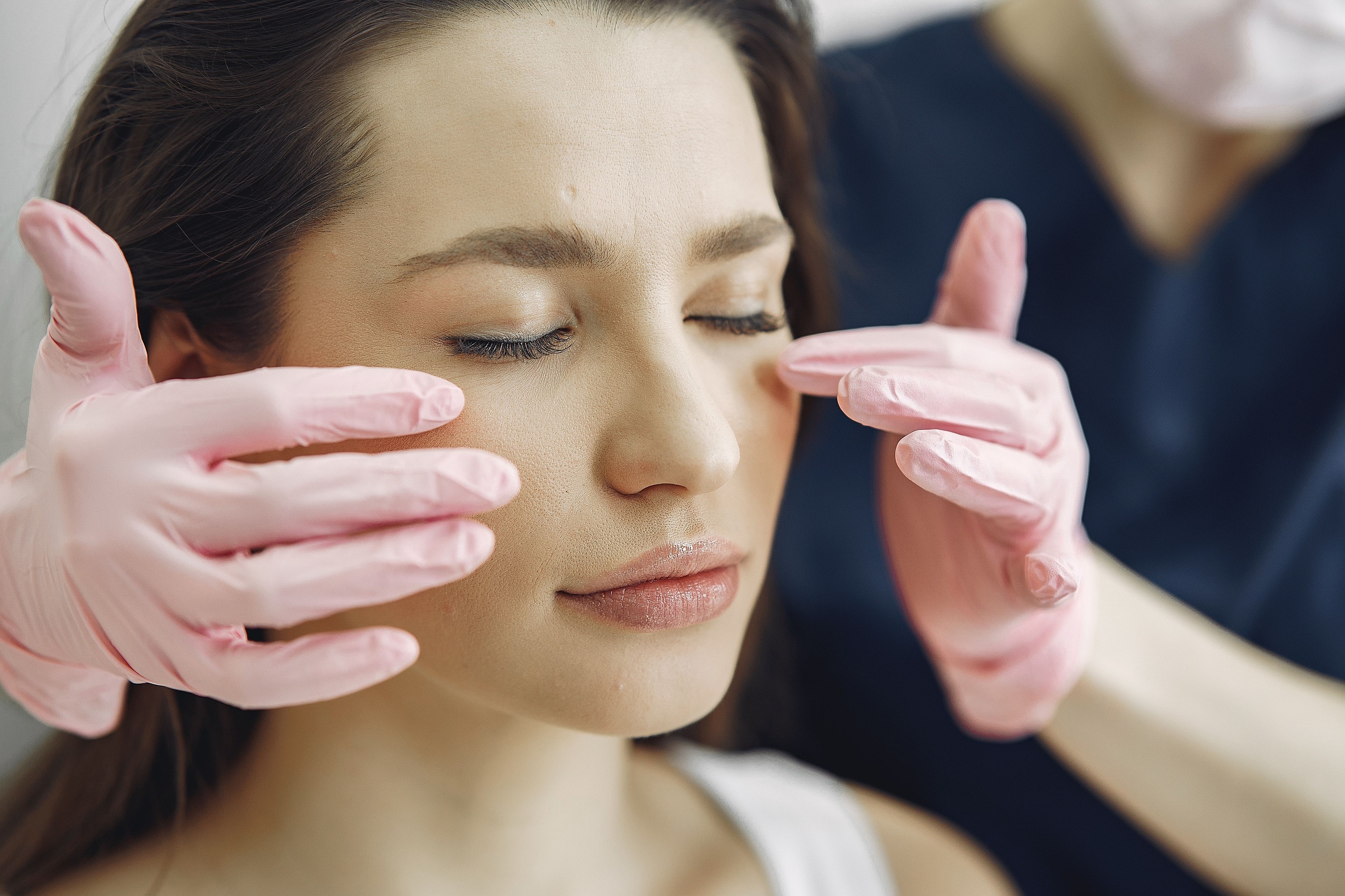 Gloved hands gently framing a patient's face during an assessment